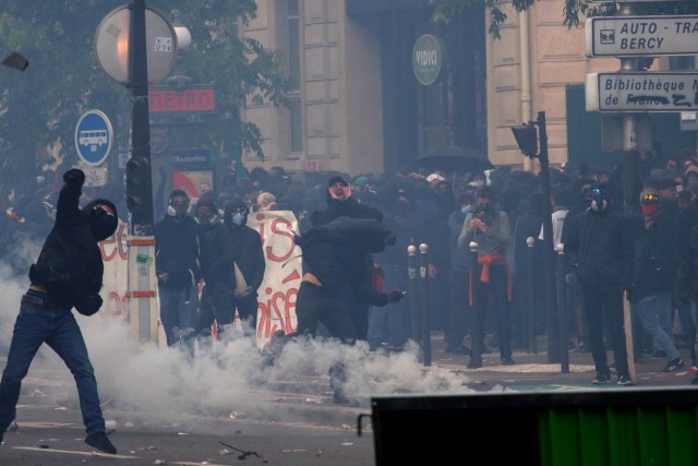 Un manifestante enmascarado arroja una piedra mientras el gas lacrimógeno flota en el aire durante los enfrentamientos en la marcha sindical del Primero de Mayo en París, Francia, el 1 de mayo de 2018. REUTERS / Philippe Wojazer
