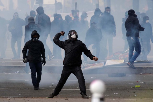 El gas lacrimógeno llena el aire cuando un manifestante enmascarado arroja una piedra durante los enfrentamientos en la manifestación sindical del Primero de Mayo en París, Francia, el 1 de mayo de 2018. REUTERS / Philippe Wojazer