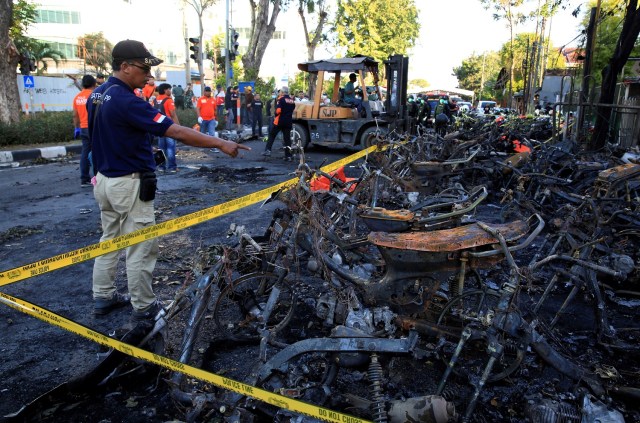 Un policía forense apunta a motocicletas quemadas tras una explosión en la Iglesia de Pentecostés Surabaya Central (GPPS), en Surabaya, Indonesia, el 13 de mayo de 2018. REUTERS / Beawiharta