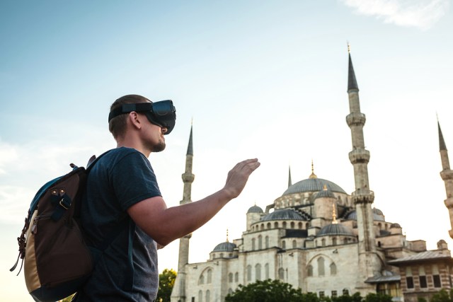 A traveler with virtual reality glasses. The concept of virtual travel around the world. In the background, the blue mosque Sultanahmet in Istanbul. Modern imaging technology.