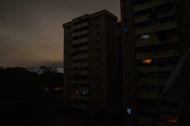 Una vista de un complejo residencial donde la gente usa luz de teléfonos celulares o velas durante un apagón parcial en el barrio La Carlota de Caracas el 14 de mayo. (Wil Riera / For The Washington Post)